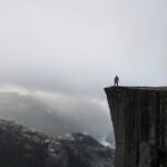 Personne debout au bord d’une falaise dans la brume