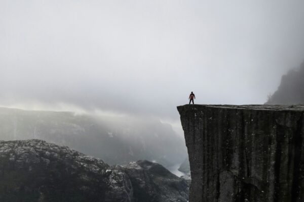 Personne debout au bord d’une falaise dans la brume