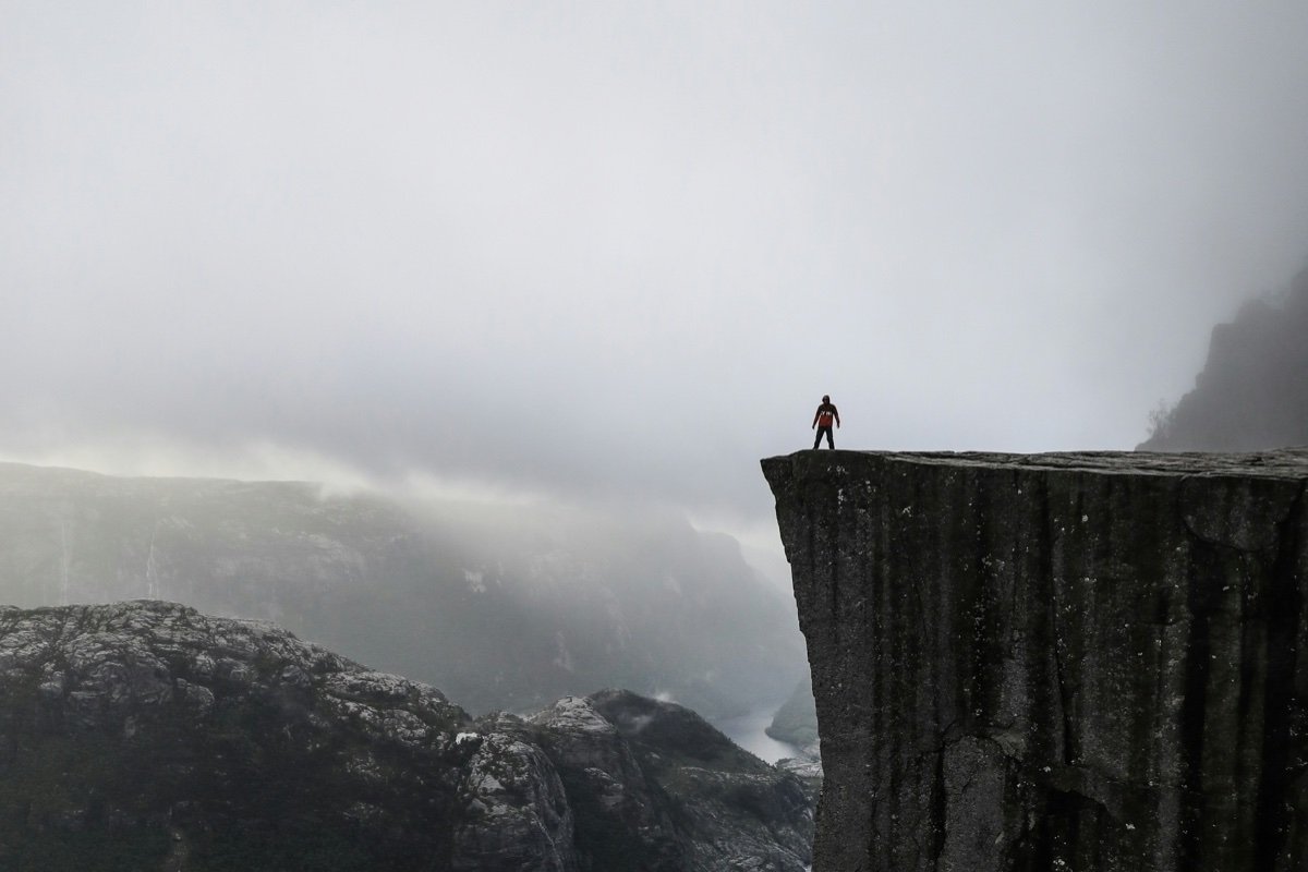 Personne debout au bord d’une falaise dans la brume